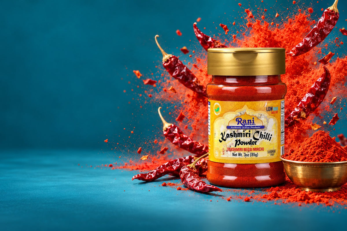 Rani Kashmiri Chilli Powder jar with a burst of red chilli powder on a teal backdrop